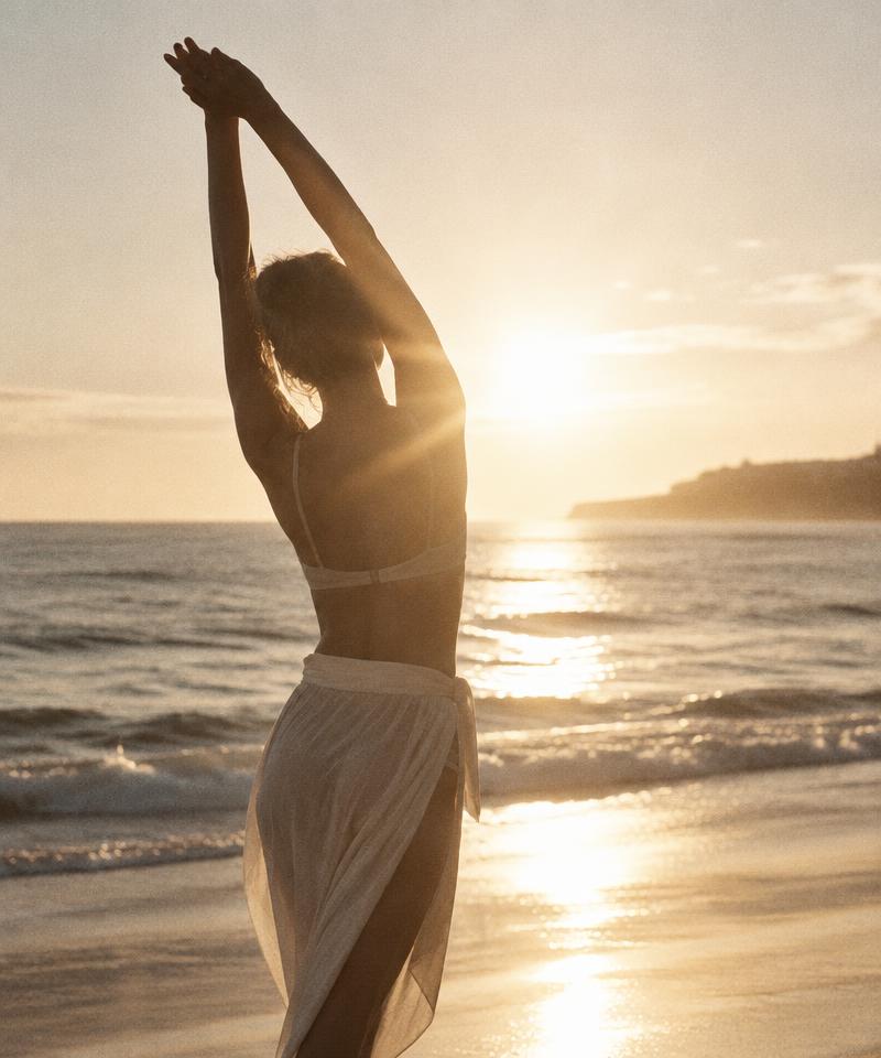 Woman stretching by the sea at sunrise
